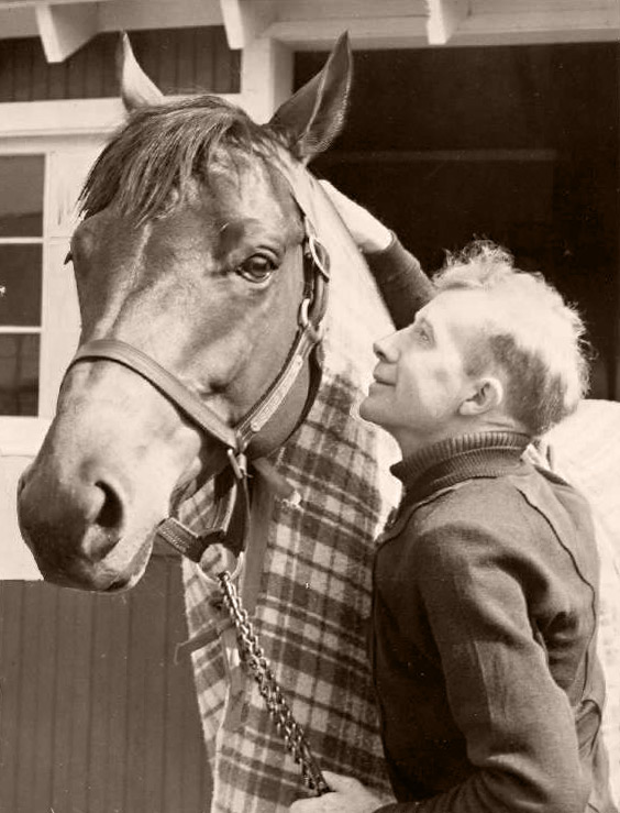 Seabiscuit standing with jockey Red Pollard in an archival photograph